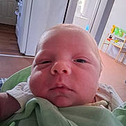 Evan is registered to the contest to win money with this photo: baby, newborn, close_up, face, infant, blanket, indoors, person, sleepy, curious, home, kitchen, furniture, light, skin, head, eyes, nose, mouth, newborn_baby