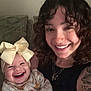 baby, bow, smile, woman, curly_hair, nose_ring, laughing, couch, blanket, tattoo, jewelry, necklace, indoor, person, happy, clothing, infant, family, portrait, cute
