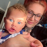 Jamir joined the competition — help win amazing prizes! baby, child, woman, glasses, red_hair, curly_hair, tattoo, indoor, portrait, holding, skin, face, hand, smile, person, casual_clothing, light, door, room, happy