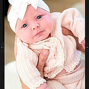 Lynnleigh is registered to the contest to win money with this photo: baby, baby_clothes, blue_eyes, bow, child, closeup, cute, expression, hand, headband, holding, indoor, infant, knitwear, newborn, person, pink_clothing, portrait, skin, soft_light