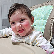 Helen is registered to the contest to win money with this photo: baby, child, high_chair, smiling, happy, indoor, face, cheeks, clothing, person, cute, nose_ring, earrings, seat, feeding_chair, infant, young_child, expression, playful, portrait