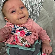 Athena is registered to the contest to win money with this photo: baby, infant, child, pink_clothing, floral_pattern, baby_seat, cushion, face, hand, smile, eyes, cute, portrait, indoors, fabric, pattern, sitting, young_child, soft_texture, comfort