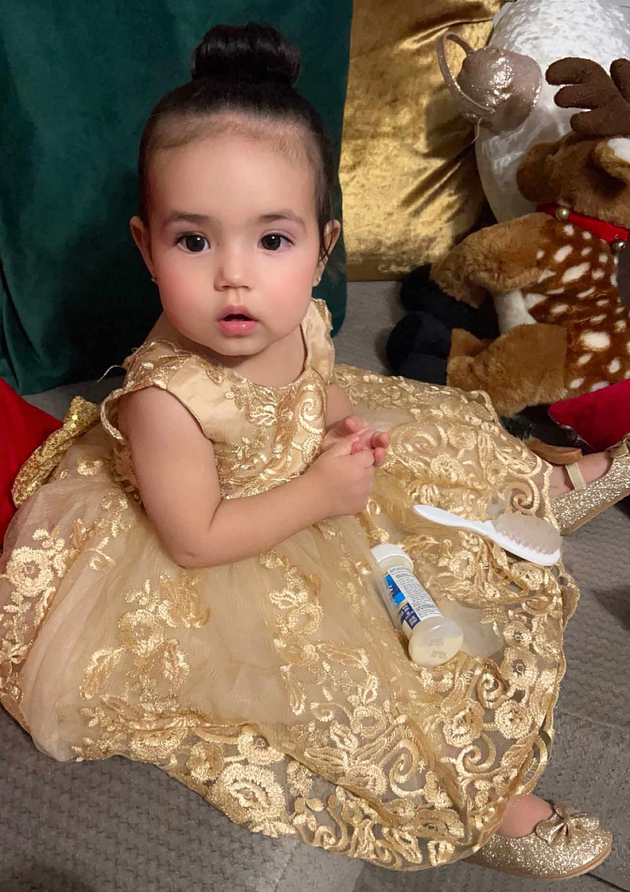Angel is registered to the contest to win money with this photo: toddler, child, girl, dress, gold, sparkle, shoes, sitting, plush_toy, couch, curly_hair, bun_hairstyle, indoor, cute, face, portrait, expression, clothing, baby, decor