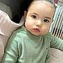 Angel is registered to the contest to win money with this photo: child, toddler, baby, face, sweater, green_clothing, indoors, furniture, chair, blanket, curly_hair, person, portrait, cute, home, baby_gate, soft_lighting, seated, expressionless, earrings