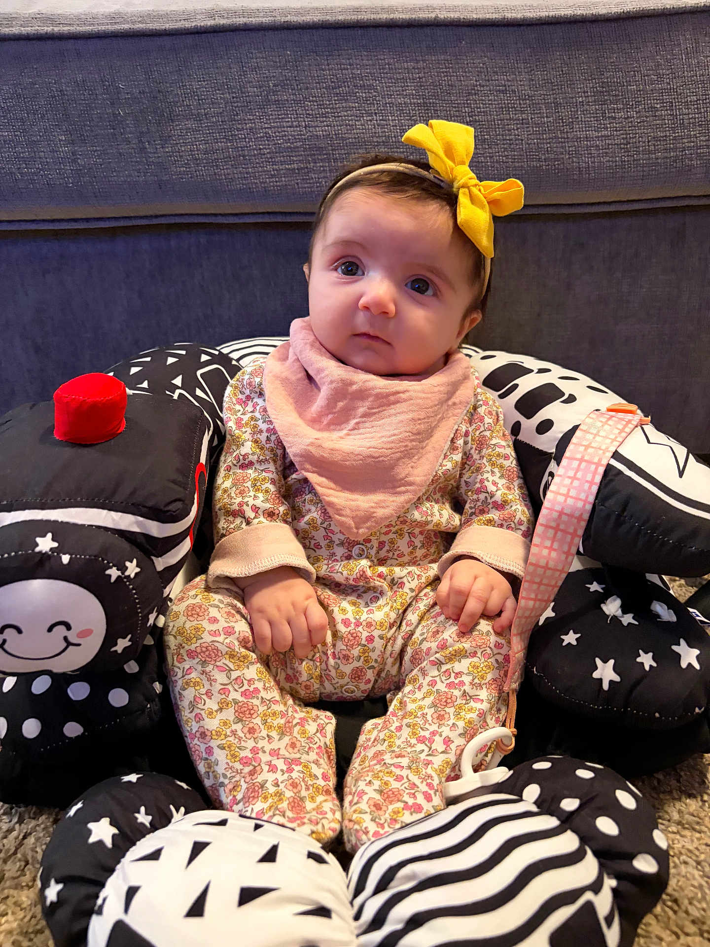 Francesca joined the competition — help win amazing prizes! baby, infant, child, headband, yellow_bow, bib, floral_pajamas, hands, toys, black_and_white_toys, plush, sofa, cushion, carpet, pacifier_clip, portrait, wide_eyes, sitting, indoors, cute