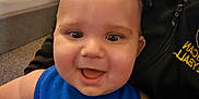 Viktor is registered to the contest to win money with this photo: baby, child, smiling, happy, blue_bib, spiky_hair, indoor, person, hoodie, carpet, bed, blanket, face, closeup, infant, holding, cheerful, room, casual, portrait
