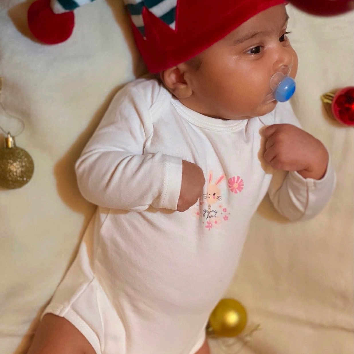 Divit a rejoint le concours — aidez-le/la à gagner de superbes lots ! baby, child, christmas_ornaments, chubby_legs, cute, decorations, elf_hat, festive, headwear, holiday, holiday_spirit, indoors, infant, lying_down, onesie, pacifier, portrait, seasonal, sleepwear, soft_blanket