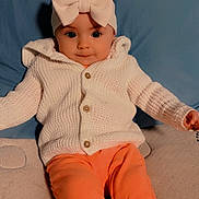 Athena is registered to the contest to win money with this photo: baby, blue_cushion, bow, casual_clothing, child, comfortable, couch, cozy, cute, face, headband, indoors, infant, knit_sweater, orange_pants, person, portrait, sitting, smiling, soft_lighting