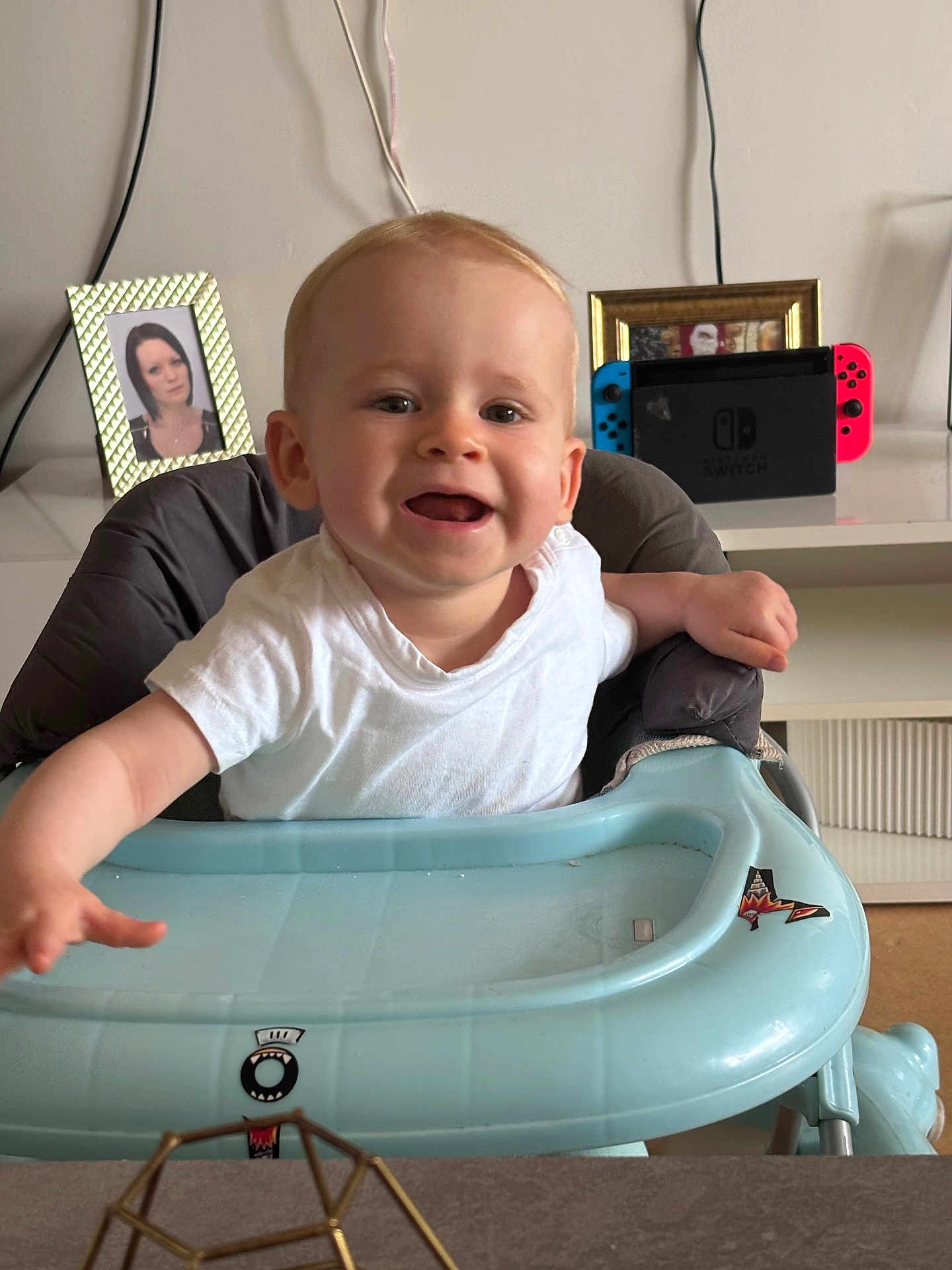 Allix participe au concours pour gagner de l'argent avec cette photo : baby, child, curious, face, furniture, happy, home, indoor, living_room, nintendo_switch, person, photograph, reaching, seat, smiling, table, toy, walker, white_shirt, young_child