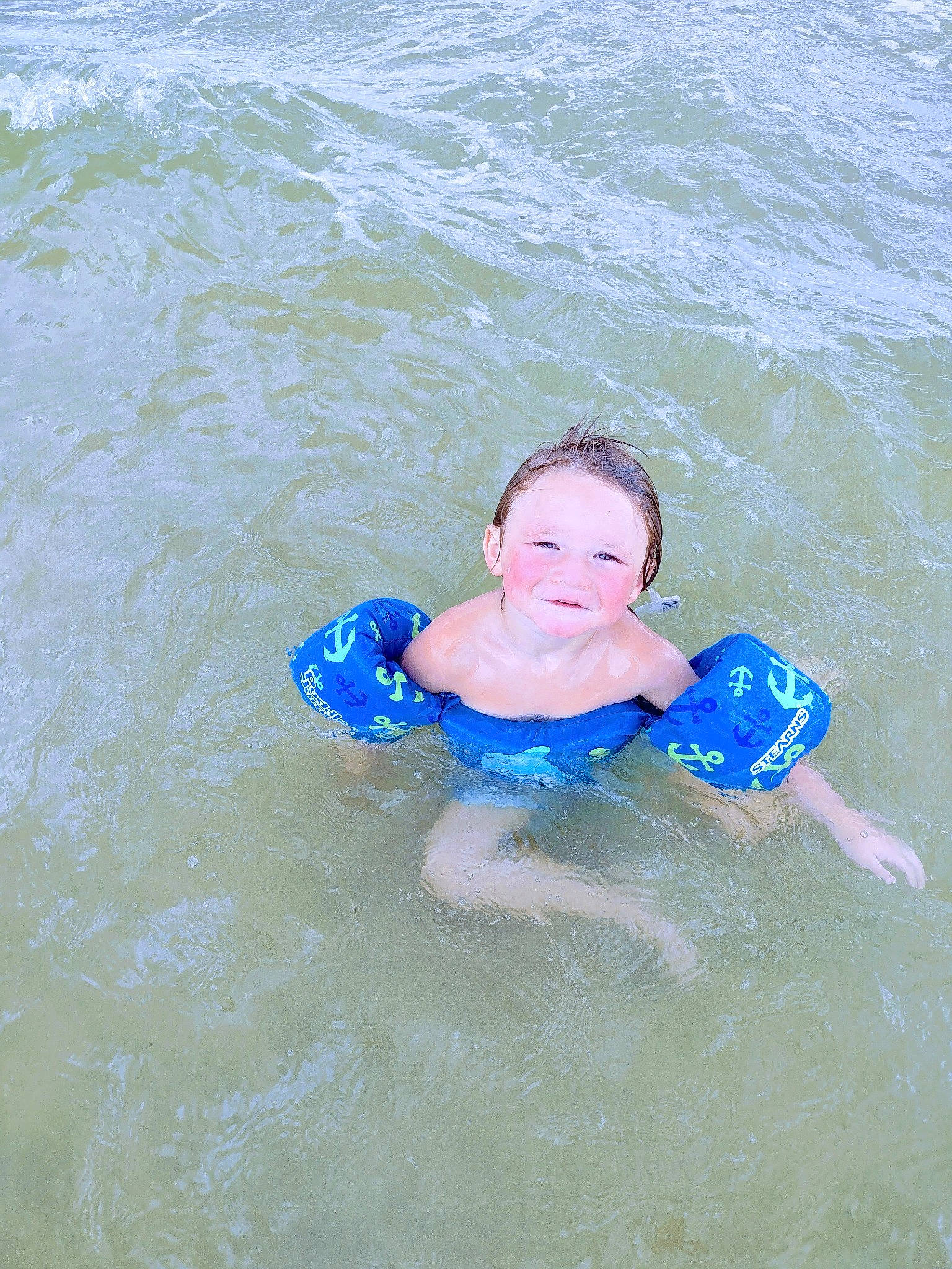 Easton is registered to the contest to win money with this photo: baby_toddler_clothing, body_of_water, child, electric_blue, fun, joy, lake, leisure, lifejacket, liquid, ocean, outdoor_recreation, person, personal_protective_equipment, play, recreation, smile, swimwear, toddler, water