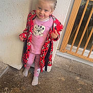 Maïna participe au concours pour gagner de l'argent avec cette photo : baby_gate, braided_hair, casual, child, concrete_floor, cozy, cute, door, footwear, glass_door, indoor, mickey_mouse, person, pink_clothing, playful, red_robe, smiling, standing, toddler, white_wall