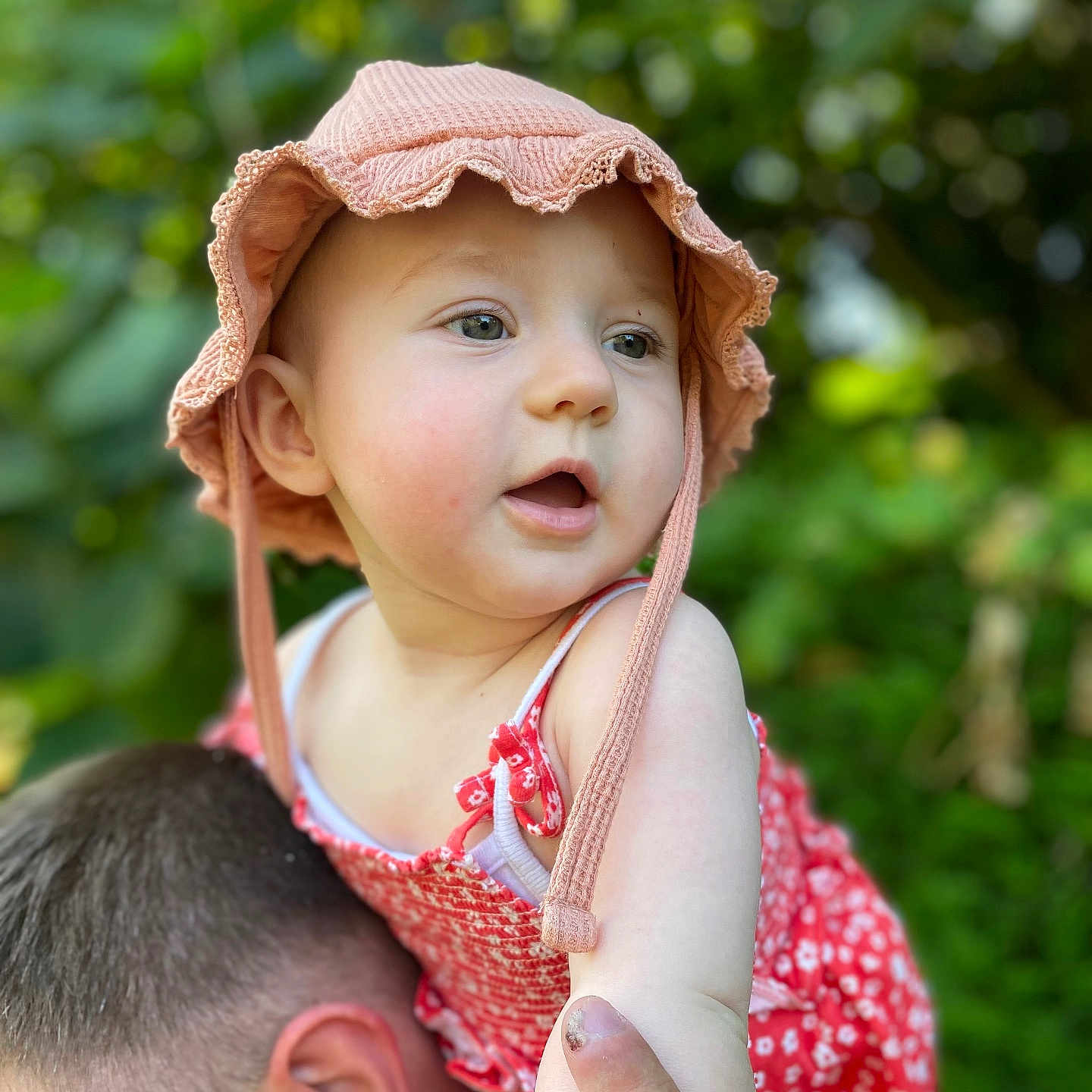 Juliette a rejoint le concours — aidez-le/la à gagner de superbes lots ! adult, baby, child, cute, floral_pattern, greenery, hand, happy, hat, head, nature, outdoor, person, pink_hat, portrait, red_dress, shoulders, skin, summer, sunlight