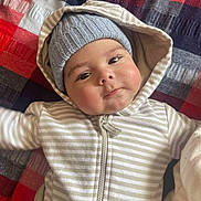 Tyzaine is registered to the contest to win money with this photo: baby, infant, child, face, hoodie, beanie, hat, striped_clothing, blanket, patchwork, cozy, cute, portrait, lying_down, indoor, warm_clothing, expression, chubby_cheeks, closeup, young