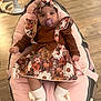 baby, baby_seat, baby_toy, child, clothing, comfort, cute, floral_dress, headband, home, indoor, infant, pacifier, person, pink_cushion, relaxing, sitting, white_socks, wooden_floor, young_child