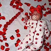 Romy a rejoint le concours — aidez-le/la à gagner de superbes lots ! baby, infant, onesie, red_bow, pacifier, rose_petals, red_hearts, sleeping, lying_down, bed, flower_arrangement, celebration, cute, soft_fabric, headband, number_two, decor, portrait, toddler, peaceful