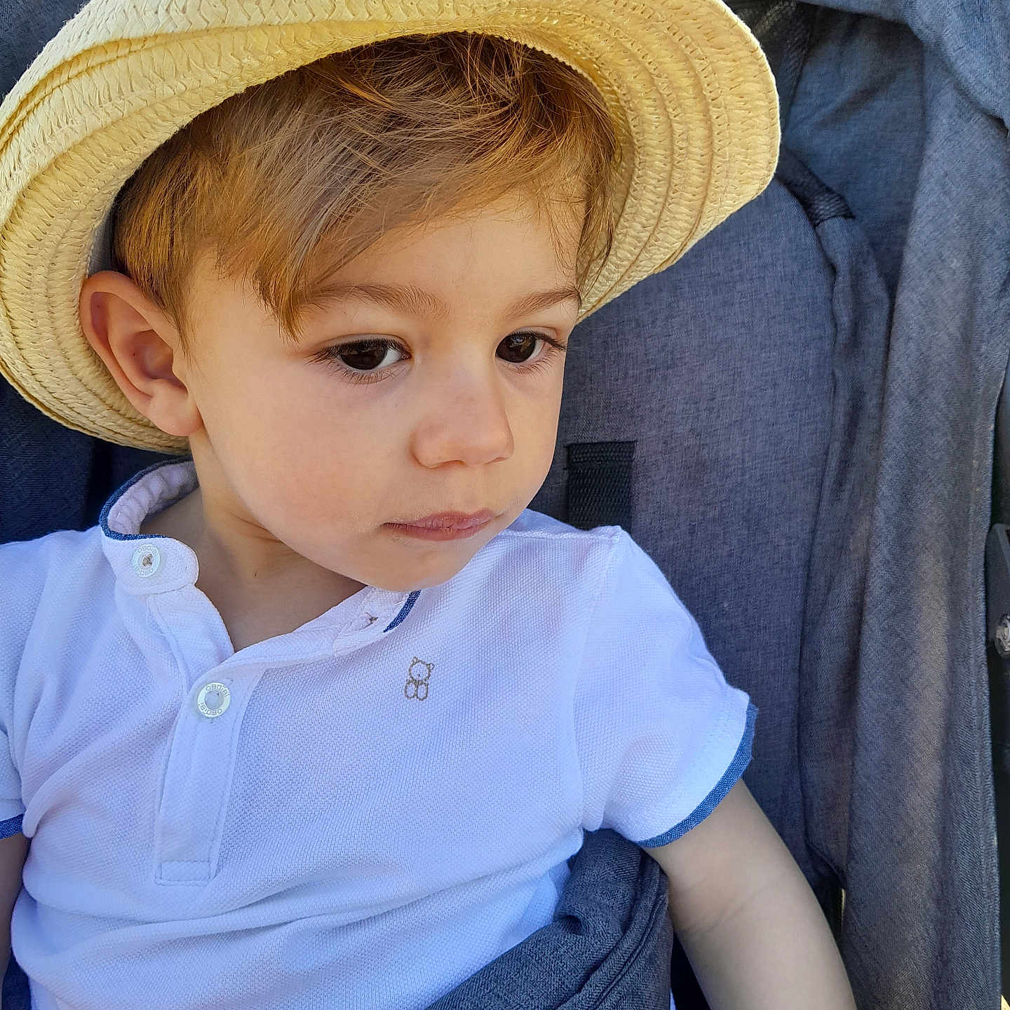 Gabriele a rejoint le concours — aidez-le/la à gagner de superbes lots ! baby, casual_clothing, child, curious, cute, face, hat, headwear, looking_away, outdoor, person, portrait, seatbelt, sitting, straw_hat, stroller, summer, toddler, white_shirt, young_child
