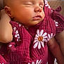 baby, sleeping, infant, blanket, maroon, daisies, flower_pattern, peaceful, closeup, face, skin, arm, hand, soft, cozy, rest, comfort, newborn, child, portrait