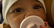 Harlow is registered to the contest to win money with this photo: baby, infant, pacifier, hat, white_hat, polka_dot, clothing, face, close_up, cute, newborn, child, portrait, indoor, baby_girl, baby_boy, skin, eyes, headwear, cozy