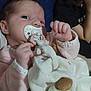 baby, pacifier, blanket, plush_toy, child, infant, face, hand, clothing, person, indoor, closeup, soft_toy, cute, sleepwear, young_child, resting, comfort, background, portrait