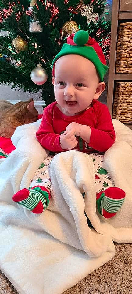 Malakai joined the competition — help win amazing prizes! baby, baby_laughing, baby_toddler_clothing, child, christmas, christmas_decoration, christmas_eve, costume_accessory, event, facial_expression, fictional_character, foot, fur, happy, holiday, human, person, sitting, small_to_medium_sized_cats, sock