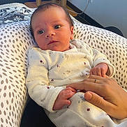 Noa a rejoint le concours — aidez-le/la à gagner de superbes lots ! adult_hand, baby, cushion, expression, eyes, face, floor, furniture, hand, holding, indoor, infant, newborn, patterned_clothing, person, pillow, power_outlet, ring, skin, white_clothing