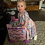 Evelyn is registered to the contest to win money with this photo: toddler, child, toy, pink, wooden, cart, indoor, carpet, living_room, furniture, dress, pigtails, blue_eyes, curious, face, person, home, play, floor, cushion