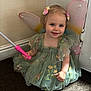 toddler, child, fairy_wings, dress, green_dress, smiling, indoor, carpet, wand, hair_clips, cute, girl, costume, playful, portrait, sitting, happy, young_child, magic, imaginative_play