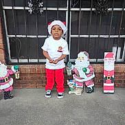 Jamari joined the competition — help win amazing prizes! bars, brick_wall, child, concrete_floor, cute, festive, holiday_decorations, holiday_spirit, outdoor, red_pants, reindeer, santa_claus, santa_hat, seasonal, smiling, sneakers, standing, white_tshirt, window, winter