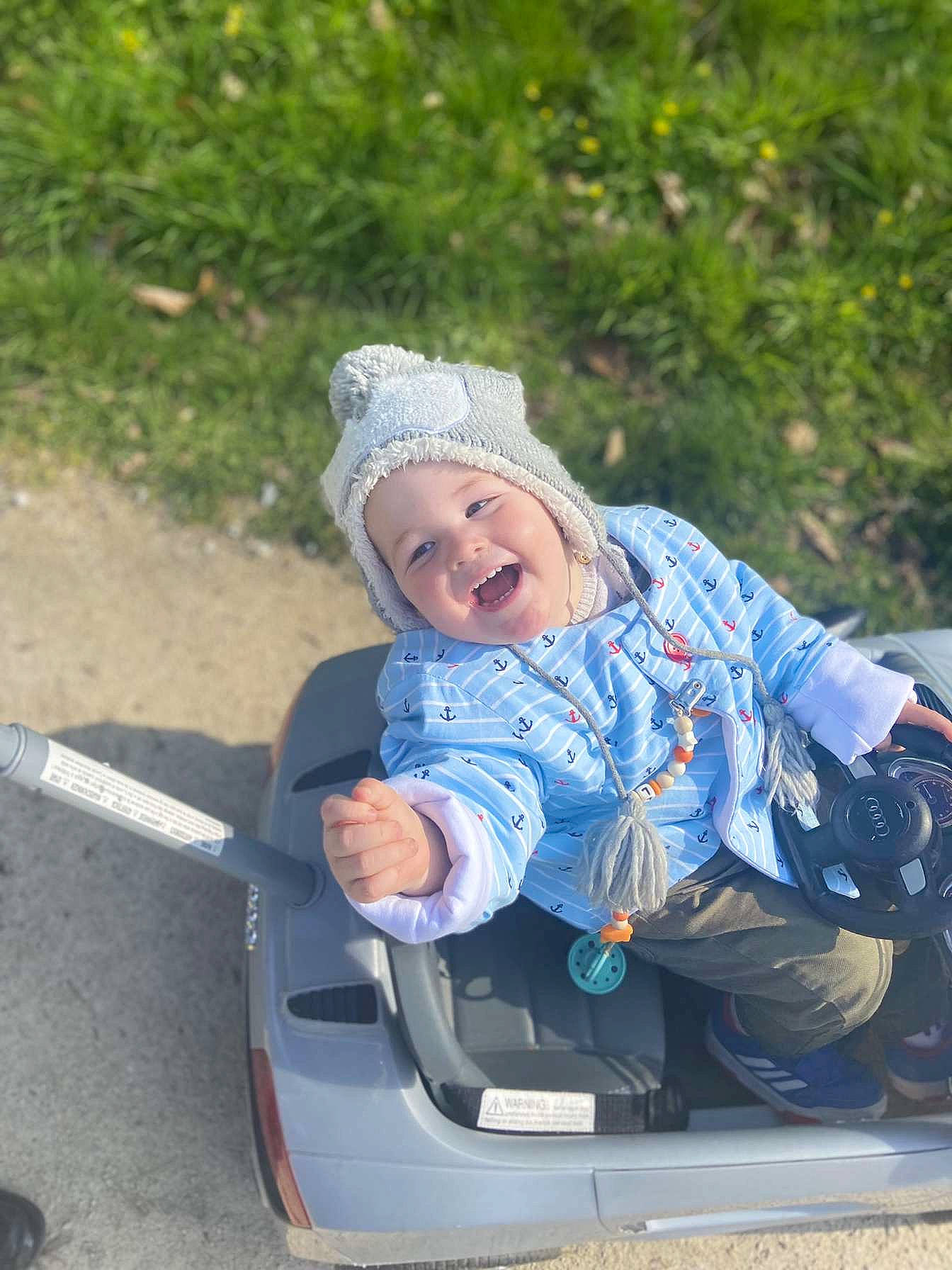 Loëvann participe au concours pour gagner de l'argent avec cette photo : asphalt, auto_part, automotive_exterior, baby, baby_carriage, baby_products, baby_toddler_clothing, electric_blue, fun, grass, happy, headwear, leisure, motor_vehicle, person, recreation, rolling, sitting, smile, toddler