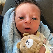Josiah is registered to the contest to win money with this photo: newborn, baby, infant, blanket, teddy_bear, mitten, clothing, face, eyes, person, portrait, cute, soft_texture, hand, couch, lap, indoors, expression, closeup, child