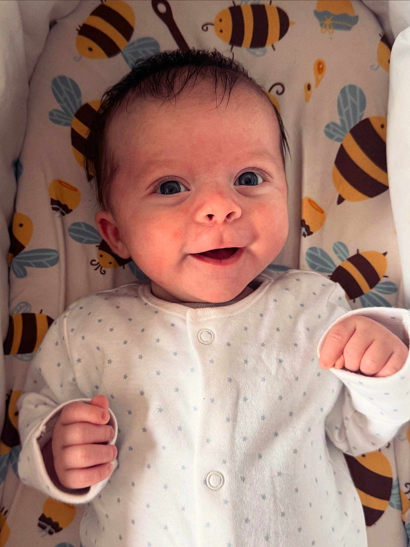 Abel is registered to the contest to win money with this photo: baby, infant, smile, face, eyes, hand, clothing, onesie, blanket, pattern, bee, cute, happy, lying_down, infant_clothing, newborn, child, portrait, soft_lighting, indoor