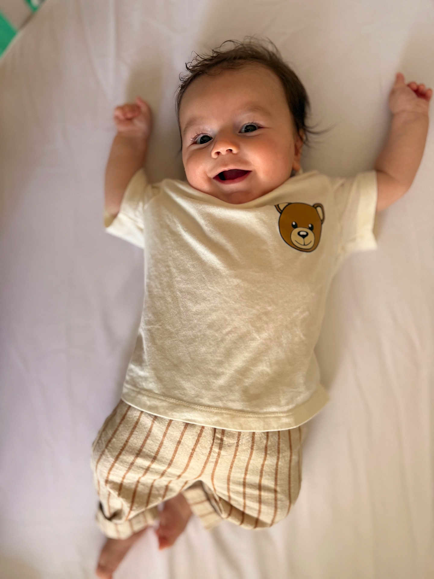 Rafael a rejoint le concours — aidez-le/la à gagner de superbes lots ! arms_up, baby, barefoot, child, clothing, cute, face, happy, indoors, infant, lying_down, person, portrait, shirt, smile, soft_light, striped_pants, teddy_bear, white_background, young_child