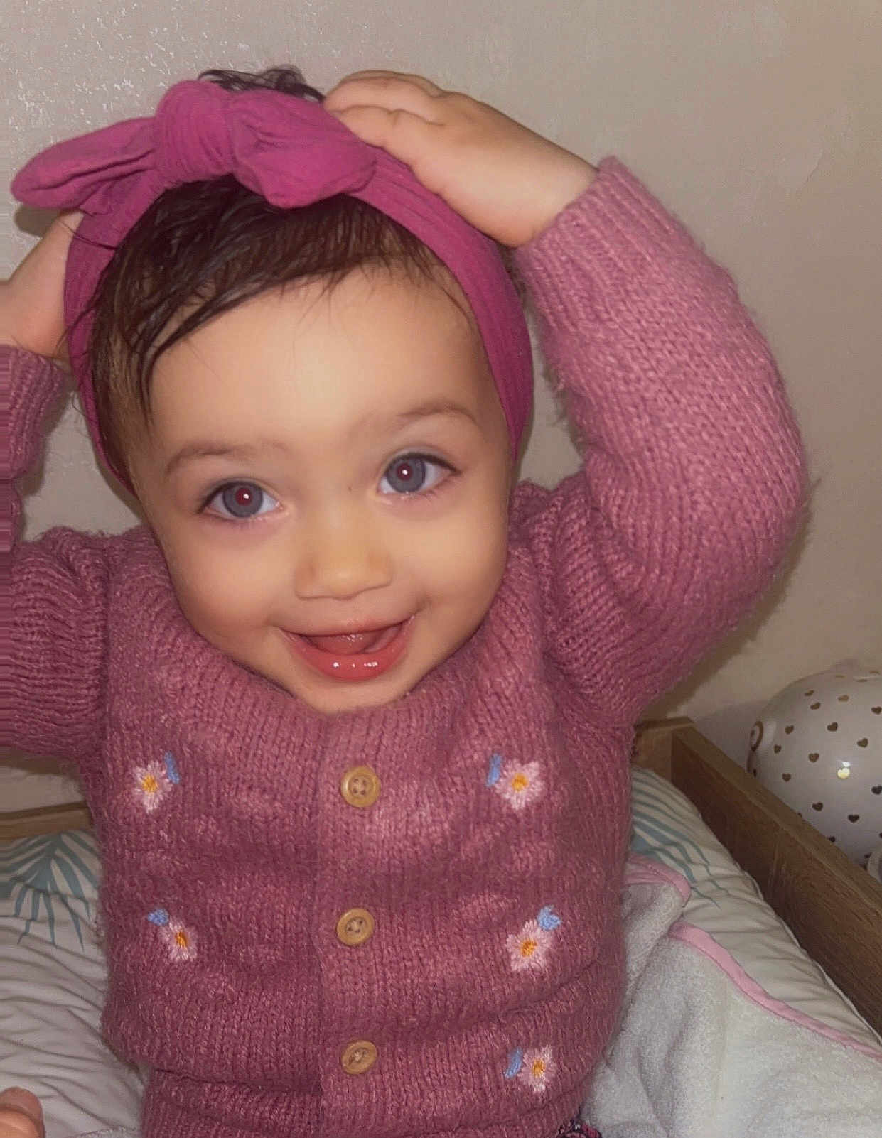 Lyna participe au concours pour gagner de l'argent avec cette photo : toddler, child, smiling, pink_sweater, headband, knitted_clothing, indoor, bed, blanket, balloon, happy, cute, portrait, person, baby, playful, hands, face, eyes, cozy