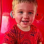 background, bright_colors, casual_clothing, cheerful, child, closeup, cute, expression, face, fun_pattern, happy, indoors, person, playful, portrait, red_shirt, short_hair, smiling, toddler, young_child