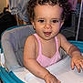 baby, child, curly_hair, cute, face, furniture, happy, high_chair, home, indoors, infant, laundry, person, pink_clothing, playtime, seat, smiling, toddler, walker, young_child