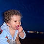 Inaïa a rejoint le concours — aidez-le/la à gagner de superbes lots ! baby, blue_clothing, blurred_background, child, closeup, curly_hair, face, hand, happy, holding, infant, joyful, night, outdoor, pacifier, person, playful, skin, smile, toy