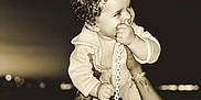 Inaïa participe au concours pour gagner de l'argent avec cette photo : adult, arms, baby, chain, child, clothing, curly_hair, face, happy, holding, infant, night, outdoor, pacifier, person, playful, portrait, sepia, smiling, tattoo