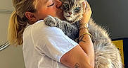 Rominet participe au concours pour gagner de l'argent avec cette photo : woman, cat, hugging, indoor, blonde_hair, white_shirt, striped_pants, tattoo, bracelets, green_eyes, fluffy_fur, affection, pet, love, portrait, casual_clothing, home, furniture, natural_light, cozy