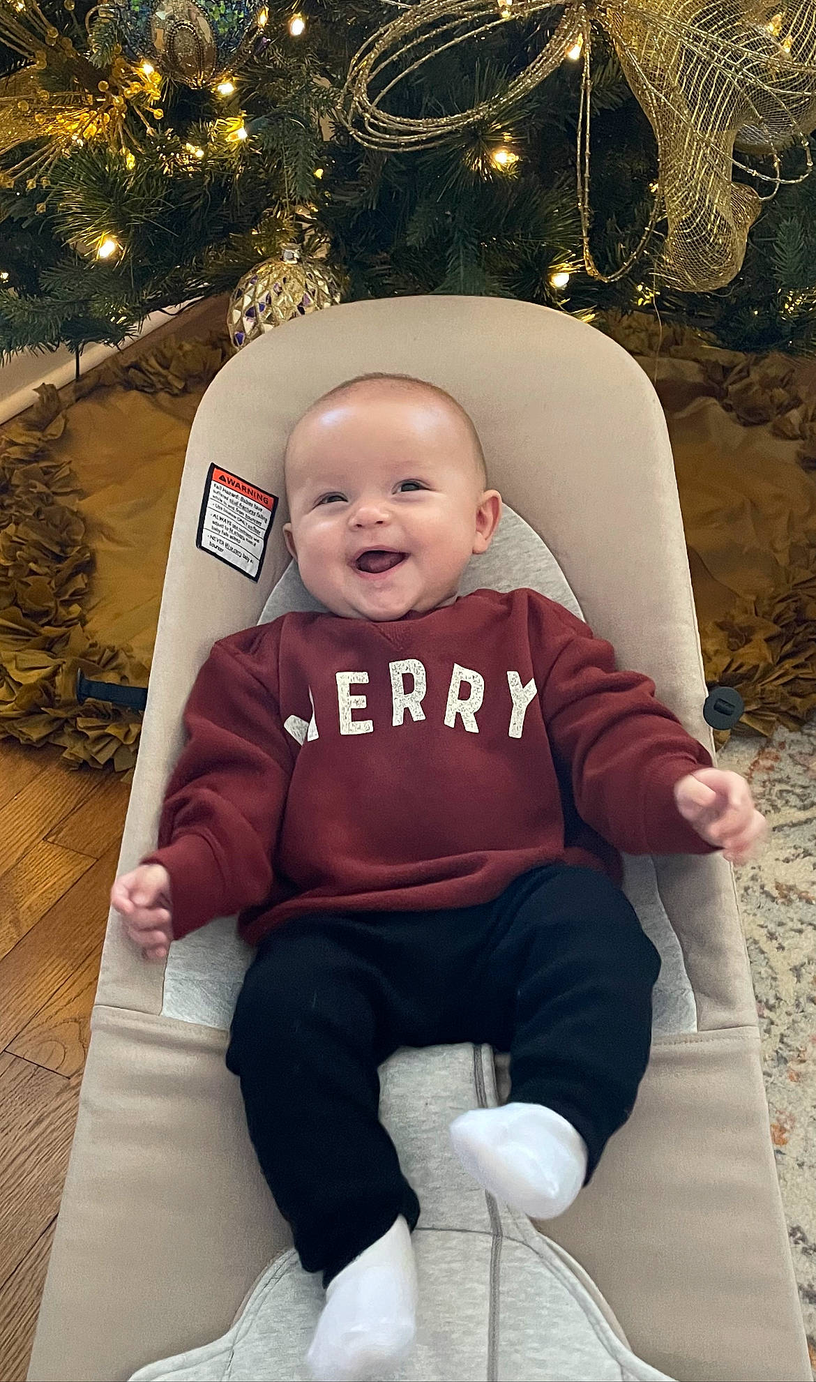 Briggs is registered to the contest to win money with this photo: baby, baby_toddler_clothing, child, christmas, christmas_decoration, christmas_tree, comfort, event, eye, happy, head, holiday, human_body, lap, person, pink, sleeve, smile, toddler, tree