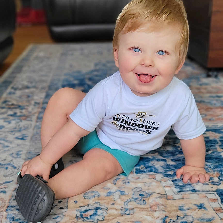 Hudson is registered to the contest to win money with this photo: architecture, baby, building, clothing, couch, cushion, face, footwear, furniture, head, homedecor, indoors, livingroom, person, photography, portrait, room, shorts, sitting, t_shirt