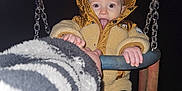 Bowen is registered to the contest to win money with this photo: toddler, child, swing, jacket, hood, night, playful, tongue_out, hand, chains, boots, outdoor, cold_weather, person, seat, clothing, holding, fun, dark_background, flash