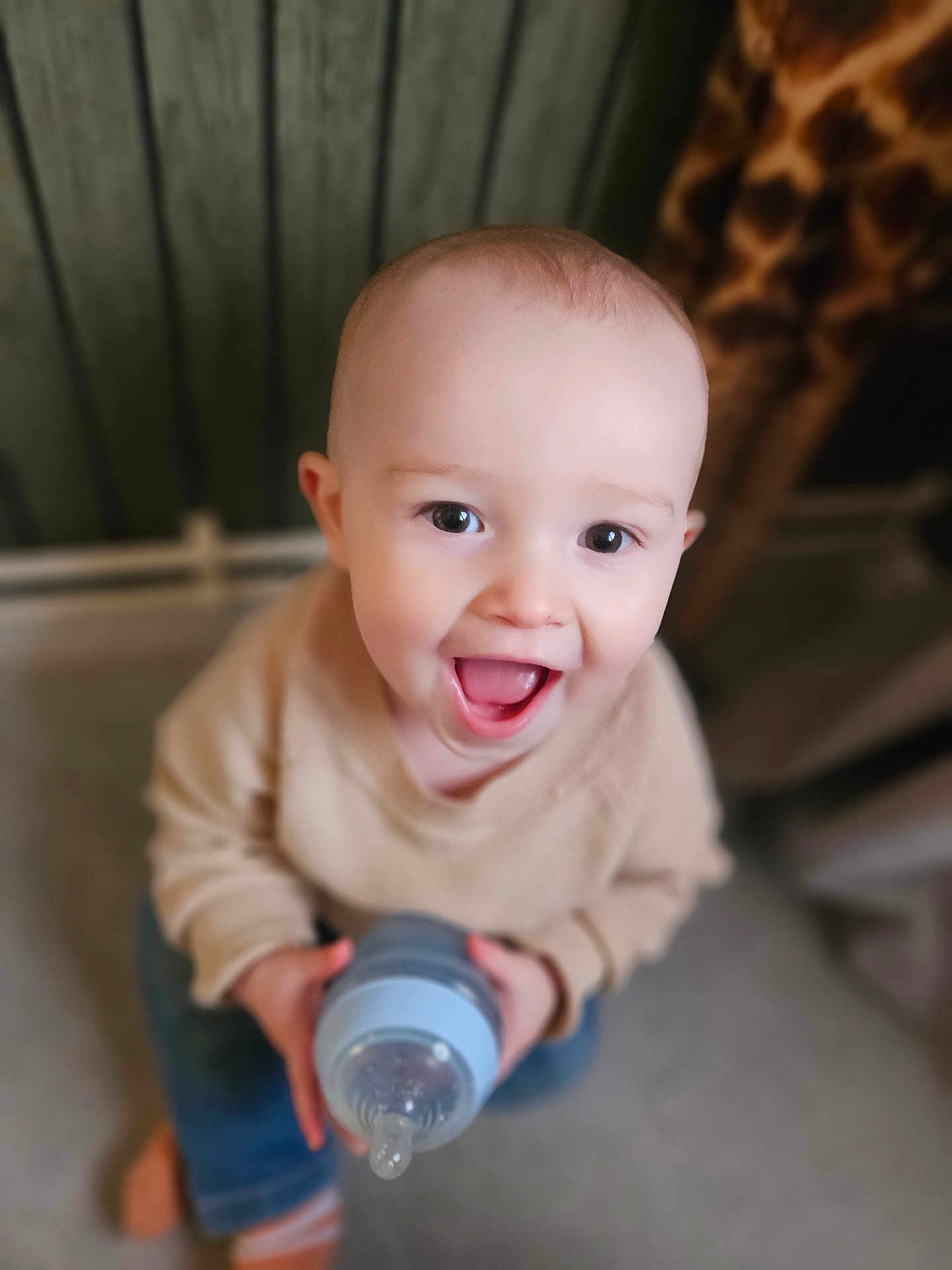 Bowen joined the competition — help win amazing prizes! baby, toddler, child, bottle, smiling, happy, indoor, clothing, sitting, face, person, cute, young_child, holding, joyful, portrait, cozy, warm_colors, expression, blurry_background