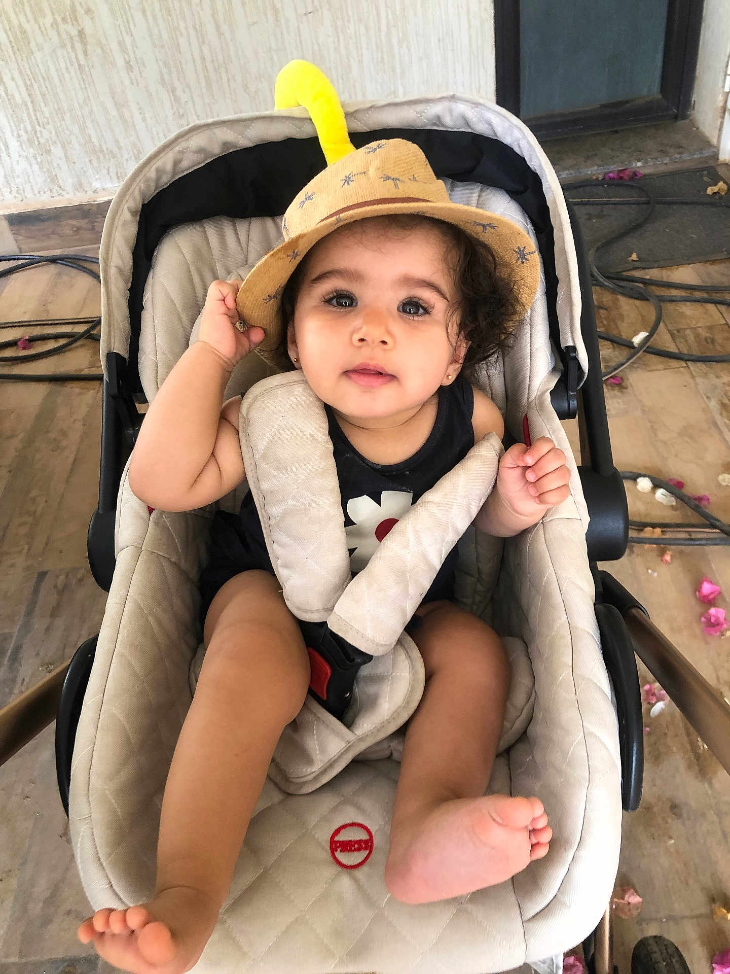 Danya participe au concours pour gagner de l'argent avec cette photo : toddler, child, stroller, hat, beige, floor, tiles, flower_petals, cables, curly_hair, cute, baby, foot, hand, clothing, seatbelt, indoor, portrait, casual, curious