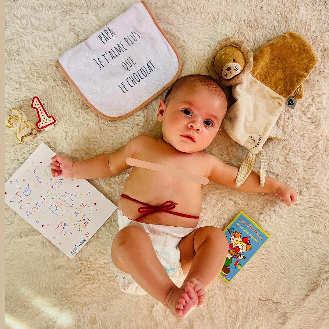 Adriann a rejoint le concours — aidez-le/la à gagner de superbes lots ! baby, baby_boy, bib, celebration, child, colorful, cute, diaper, family_love, foot, hand, handmade_card, indoor, infant, lion_plush, lying_down, plush_toy, portrait, soft_rug, soft_texture