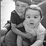 baby, child, siblings, black_and_white, smiling, curious, indoor, cozy, couch, armchair, hugging, portrait, person, cute, happy, short_sleeves, shorts, face, hair, seated