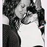 affection, black_and_white, canine, close_up, closed_eyes, collar, cuddle, curly_hair, dog, indoor, long_hair, nose_to_nose, person, pet, photography, pink_collar, portrait, sweater, tender_moment, woman