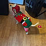 dog, costume, christmas, elf, holiday, pet, indoor, wooden_floor, trash_can, appliance, tail, curious, small_dog, decorative, red, green, white, festive, animal, household
