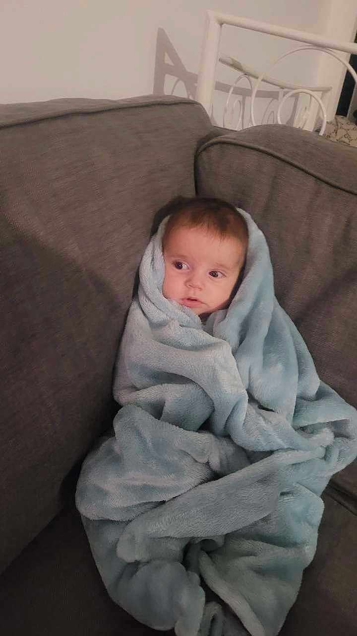 Kenzo participe au concours pour gagner de l'argent avec cette photo : baby, blanket, couch, infant, cozy, wrapped, child, face, indoor, furniture, soft, seated, portrait, comfortable, young, curious, home, warm, snug, rest