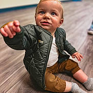 Declyn joined the competition — help win amazing prizes! child, toddler, baby, sitting, indoor, floor, wooden_floor, jacket, clothing, socks, smile, face, hand, eyes, person, cute, portrait, warm_clothing, reaching, young