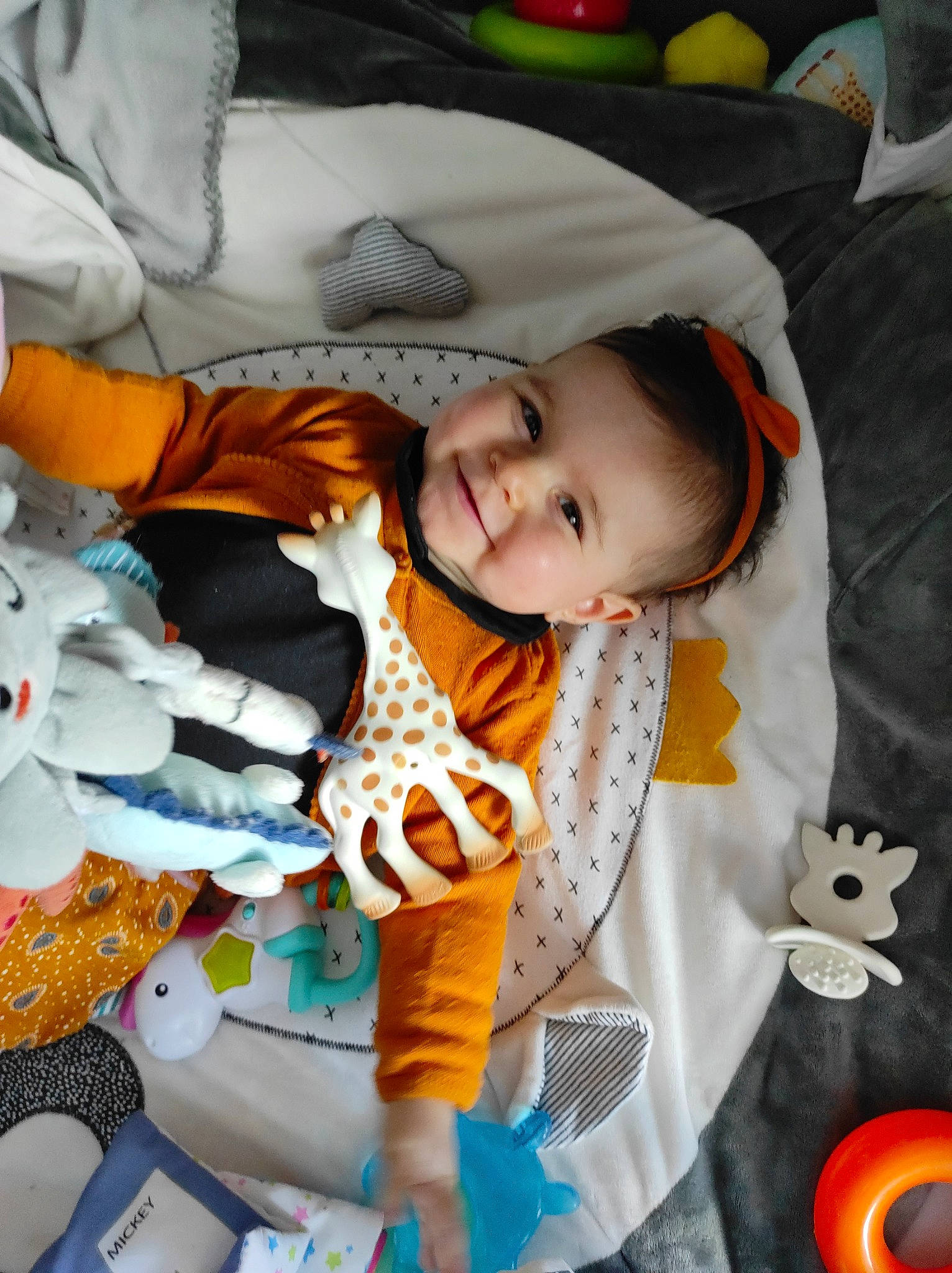 Léane a rejoint le concours — aidez-le/la à gagner de superbes lots ! baby, baby_products, baby_toddler_clothing, cheek, child, comfort, face, facial_expression, fun, happy, joy, linens, mouth, orange, person, play, skin, sleeve, smile, toddler